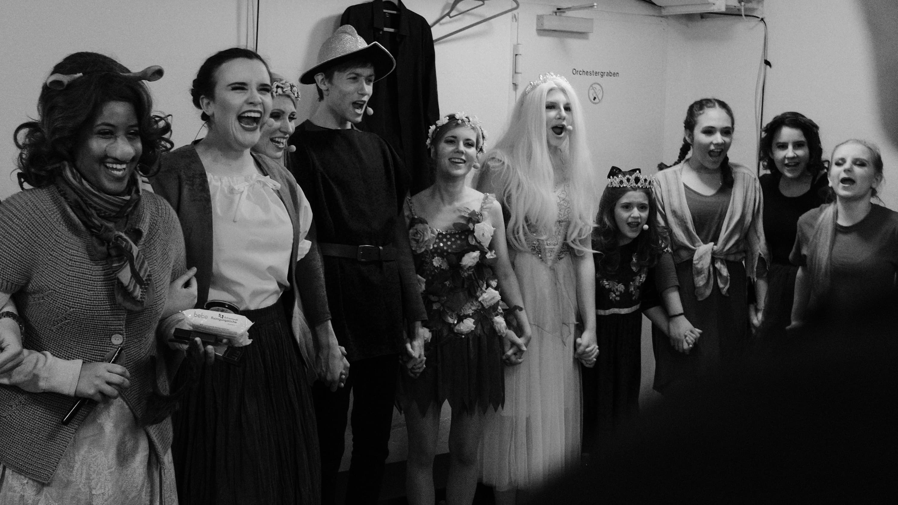 Mehrere Darsteller in Kostümen schreien sich energitisch und motivierend and.