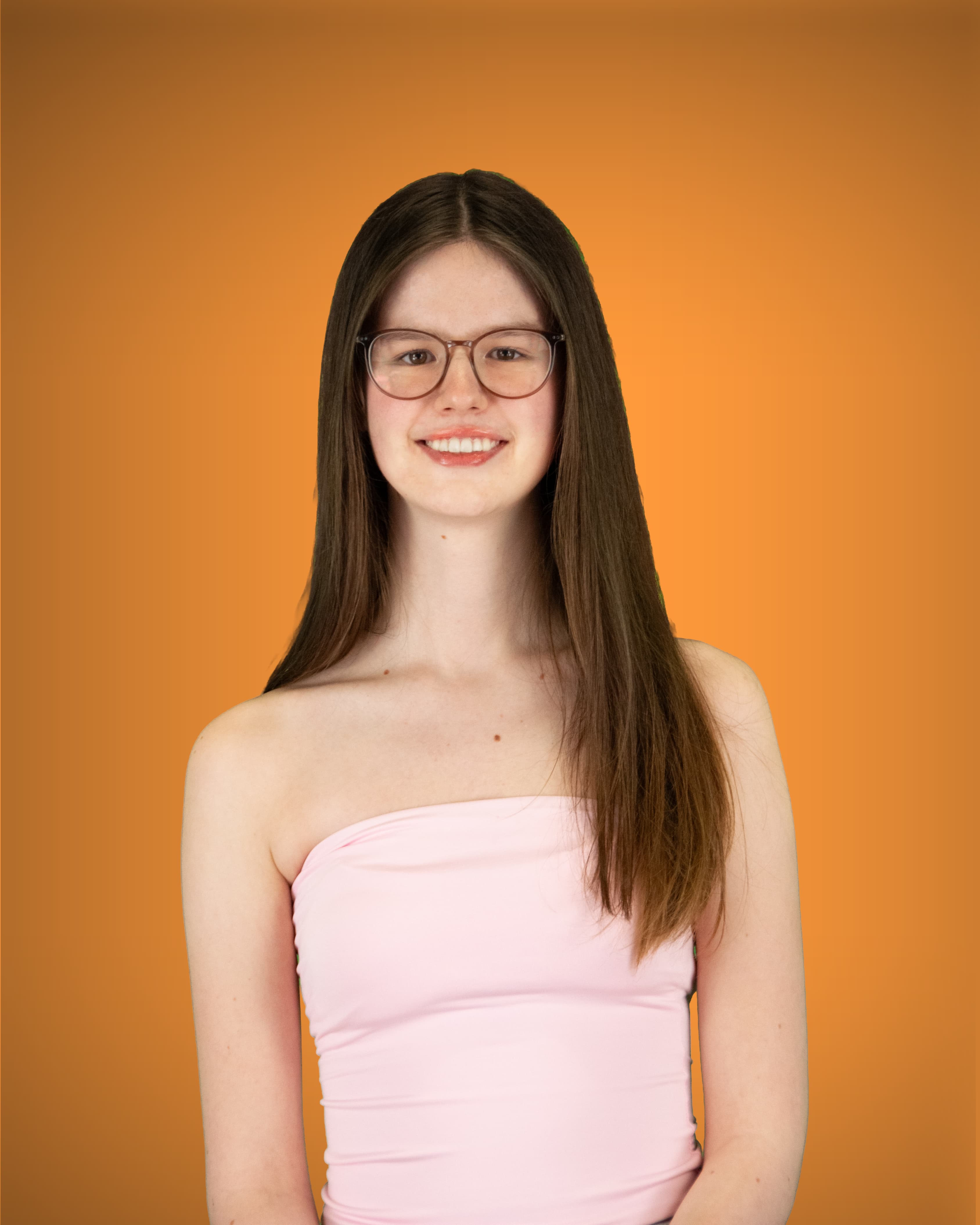 Eine junge Frau mit Brille und glatten, langen braunen Haaren blickt lächelnd in die Kamera; sie trägt ein schulterfreies, hellrosa Top.