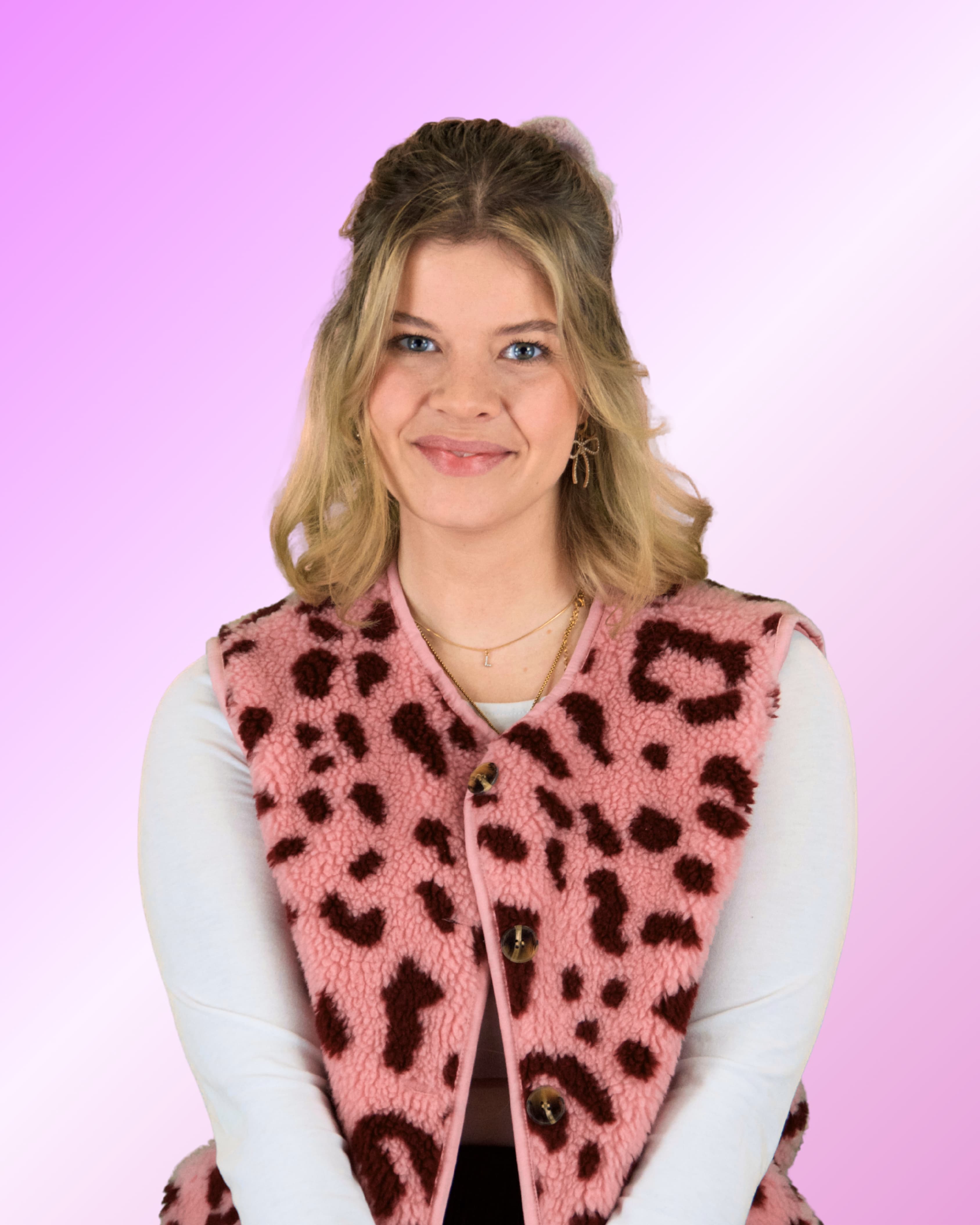 Eine junge Frau mit blondem Bob und blauen Augen blickt freundlich lächelnd in die Kamera; sie trägt eine olivgrüne Strickjacke.
