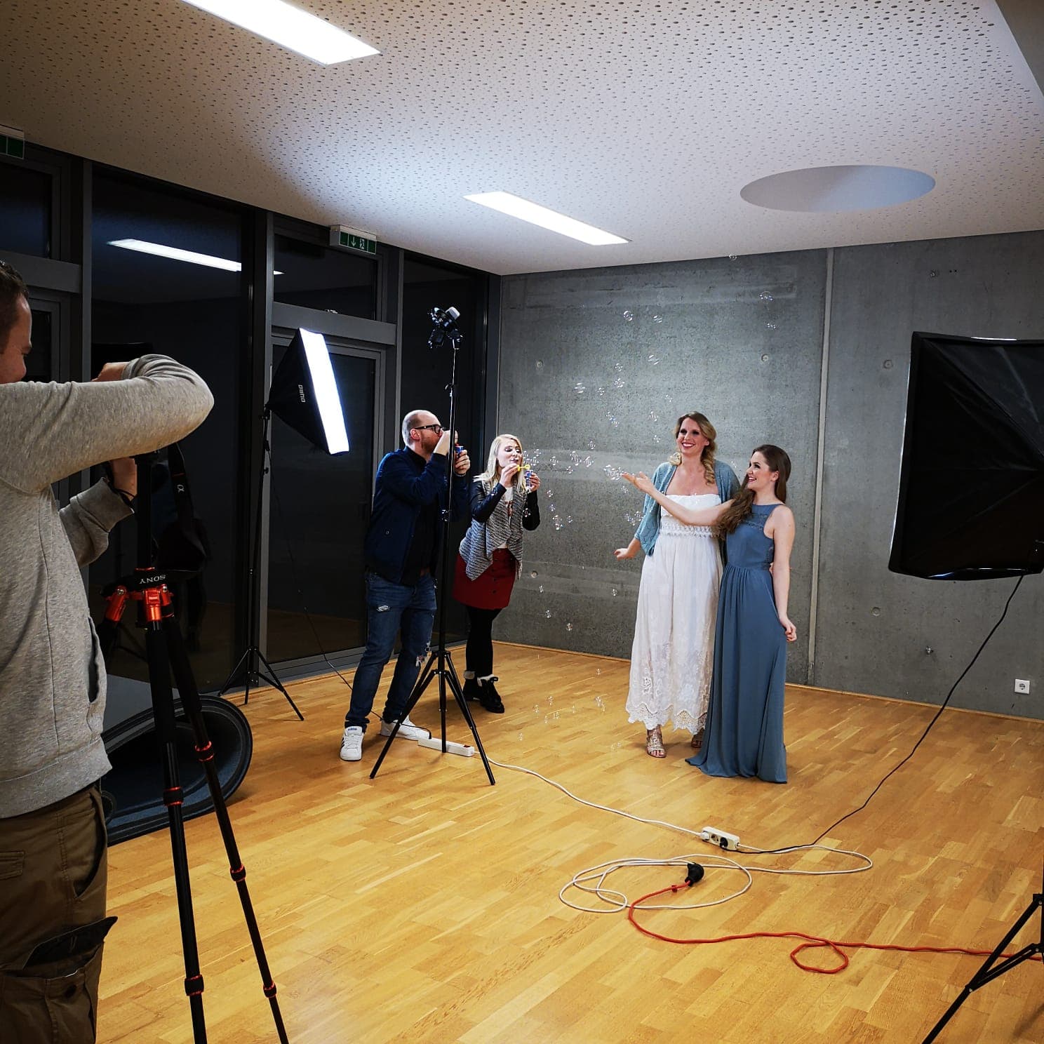 Zwei Personen in Kostüm stehen im Foto-Licht und posieren. Neben ihnen stehen zwei Personen und pusten Seifenblasen.