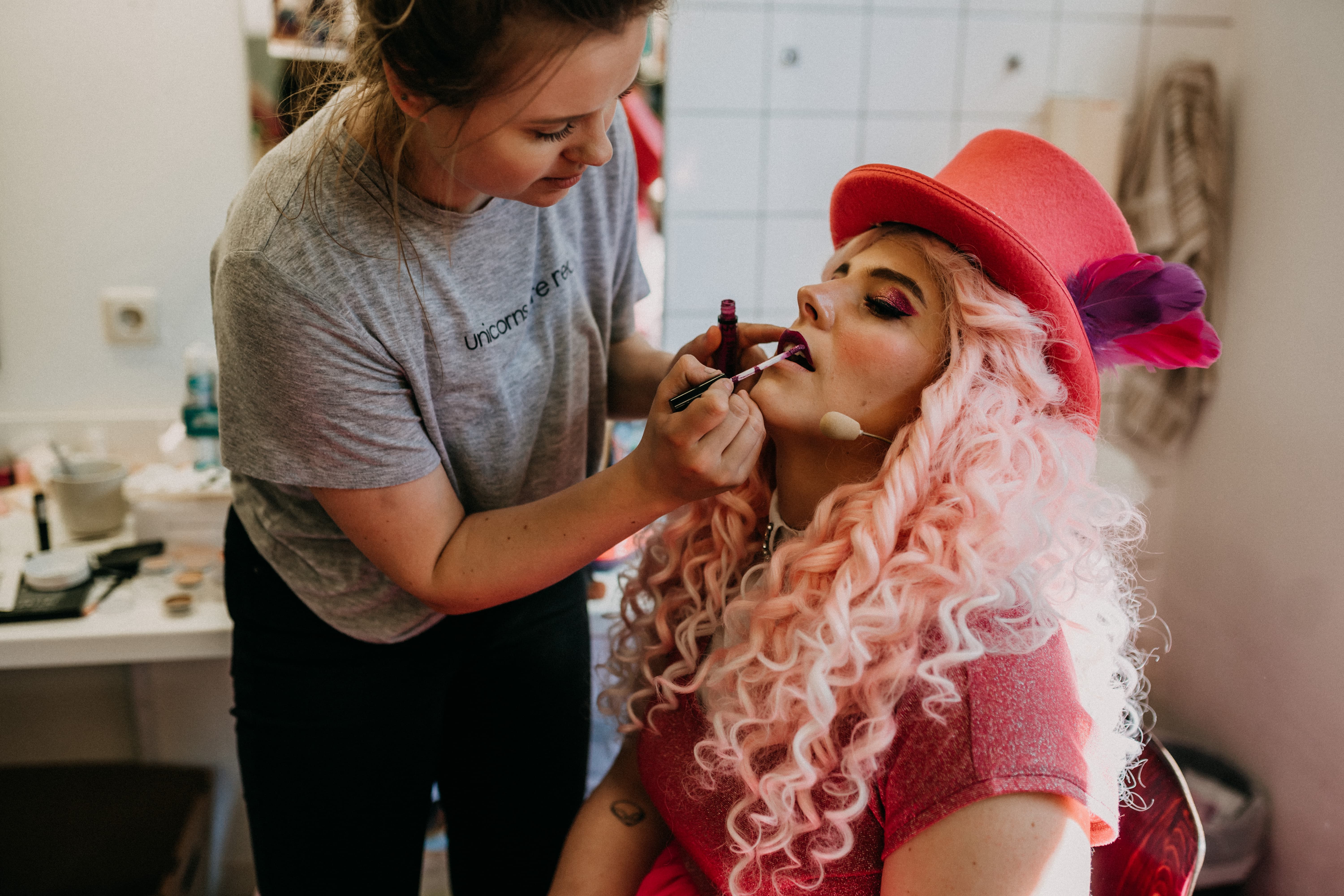 Eine Frau schminkt eine sitzende Person im Kostüm