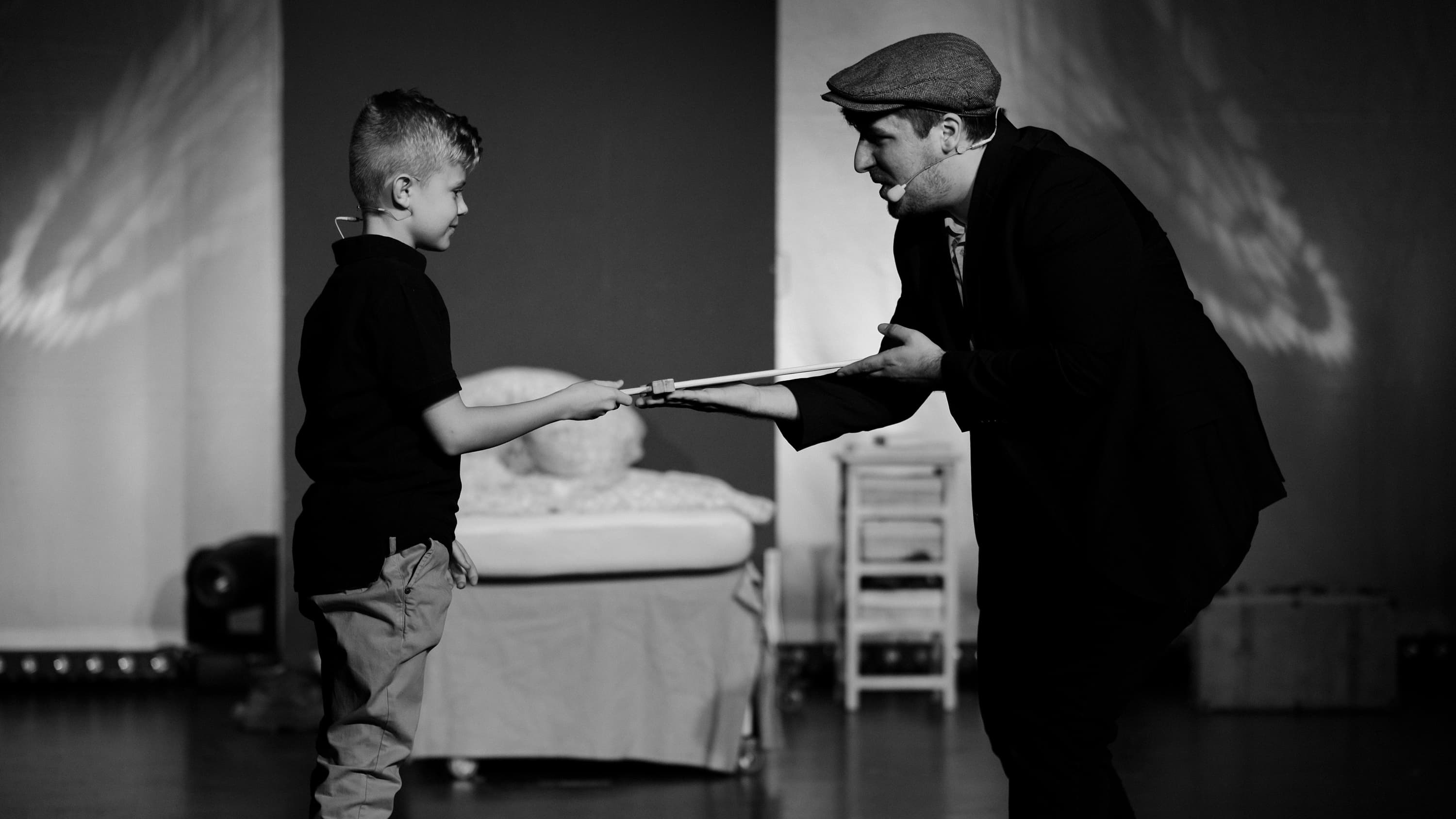 Ein Mann und sein Sohn stehen sich gegenüber. Der Mann überreich dem Jungen ein Holzschwert