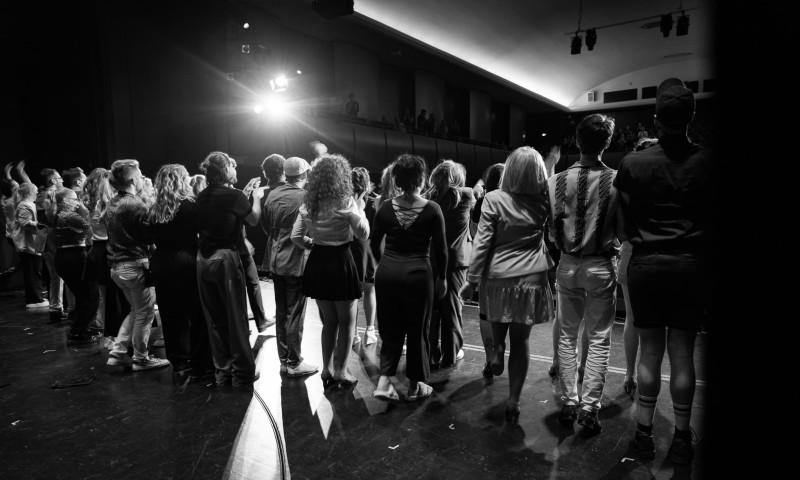 Eine Gruppe von Menschen steht auf einer Bühne in einer Reihe.