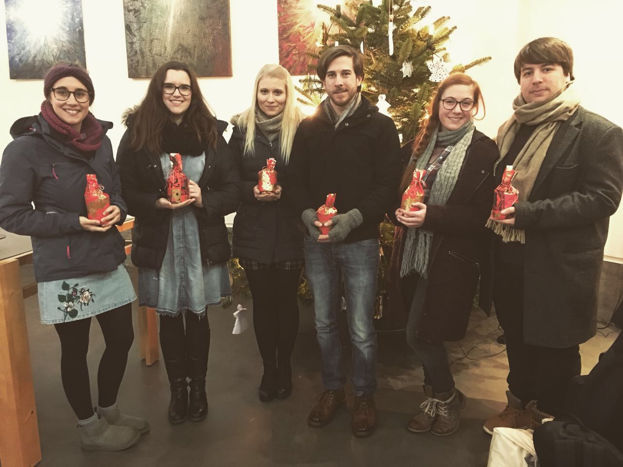 Sechs Personen stehen nebeneinander vor einem Weihnachtsbaum.